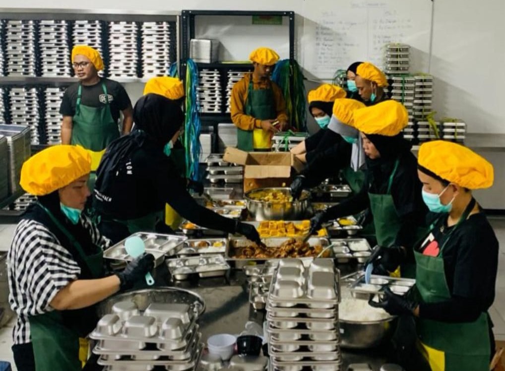 Pekerja mengemas menu Makan Bergizi Gratis di Dapur MBG saat isu pemangkasan anggaran