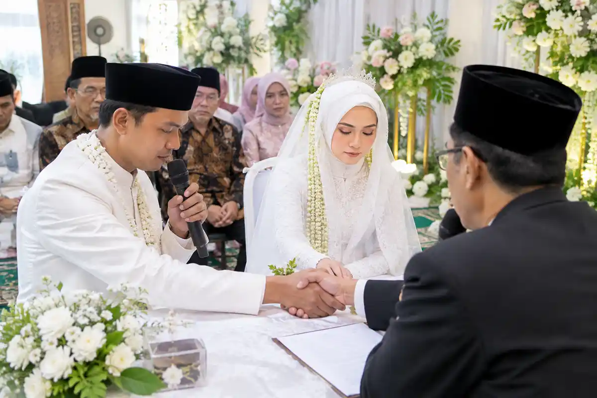Prosesi akad nikah pengantin pria dan wanita saat ijab kabul dengan wali nikah.