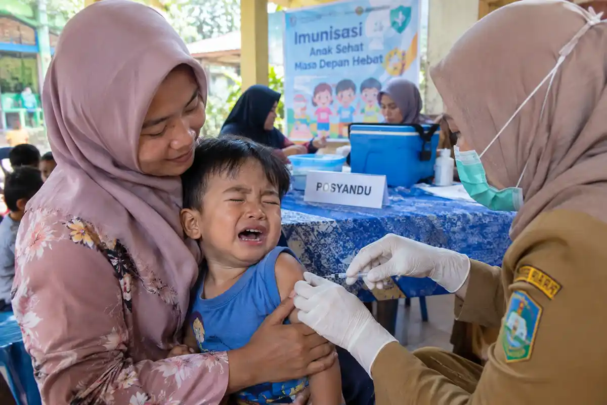 Seorang anak balita dipeluk ibunya saat mendapatkan suntikan imunisasi oleh petugas di Posyandu.