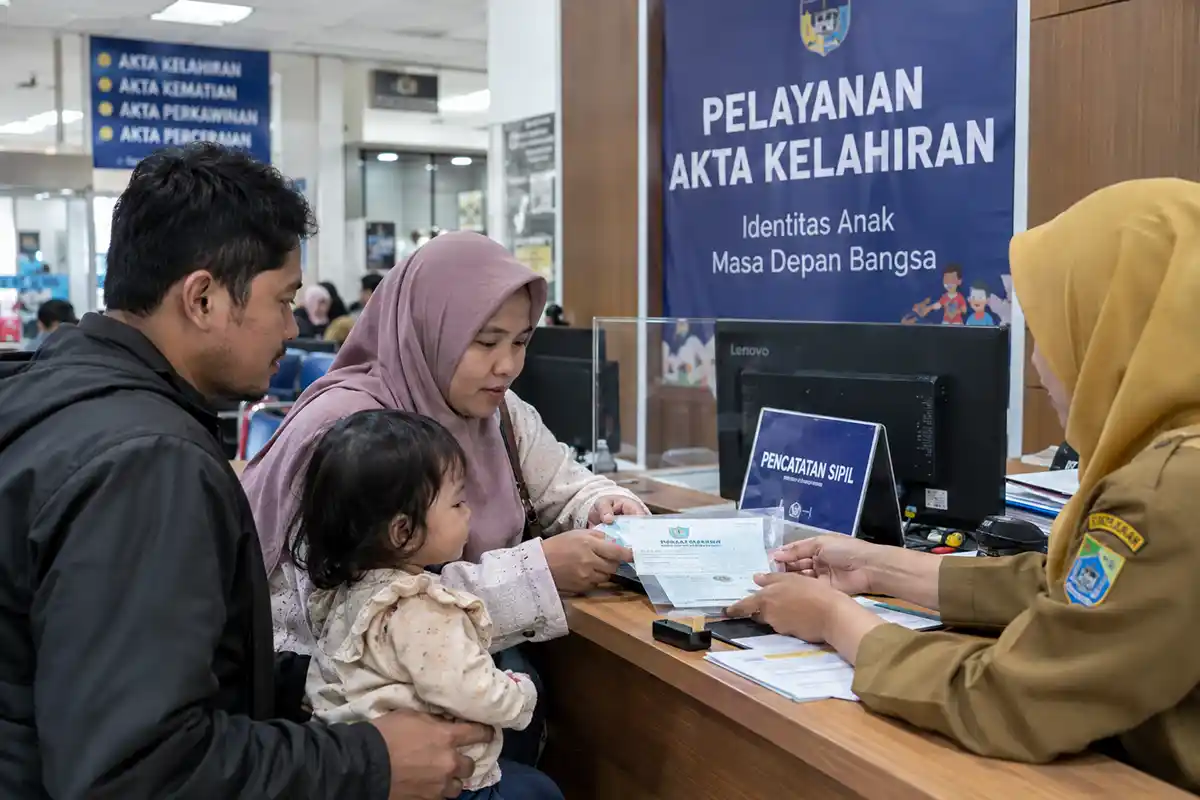 Orang tua menyerahkan berkas persyaratan di loket pelayanan Akta Kelahiran Dukcapil.